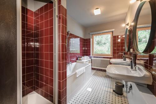 a red tiled bathroom with a tub and a sink at B&B Berglift direkt an der Talstation in Bad Hofgastein