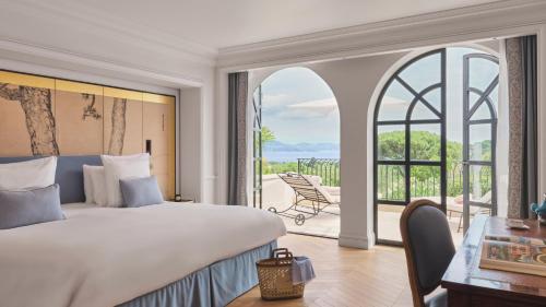 a bedroom with a large bed and a large window at Airelles Château de la Messardière in Saint-Tropez