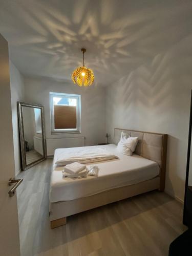 a bedroom with a bed with a mirror and a chandelier at Lisboa: Messe-/Business-/Ferienwohnung in Hilden
