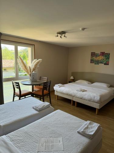 Cette chambre comprend deux lits et une table avec des chaises. dans l'établissement Hôtel La Métairie & Piscine, à Cordes-sur-Ciel
