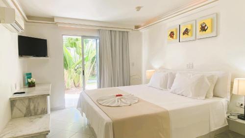 a bedroom with a large white bed and a window at New Casablanca Praia Hotel in Paulista