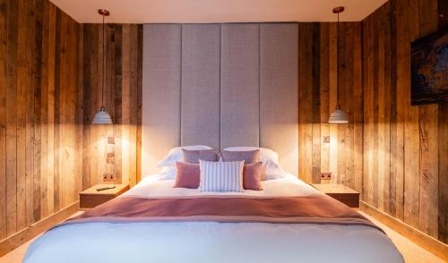 a bedroom with a large white bed with wooden walls at The Stroud Hotel in Stroud