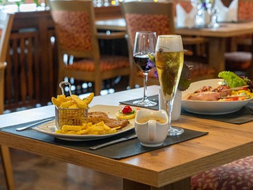 a table with a plate of food and a glass of wine at Best Western Hotel Heidehof in Hermannsburg