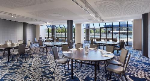 a dining room with tables and chairs and windows at Crowne Plaza Melbourne by IHG in Melbourne