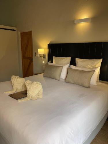 a large bed with white sheets and pillows at The Baobab Bush Lodge and Villa in Hoedspruit