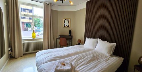 a bedroom with a large white bed and a window at Hotell Slottsgatan in Oskarshamn