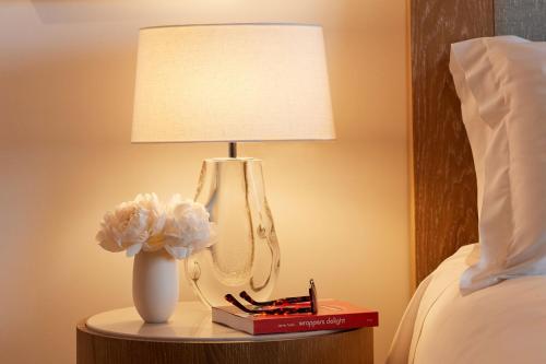 a lamp on a table next to a bed at The Maybourne Beverly Hills, Maybourne in Los Angeles