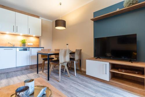 a kitchen and dining room with a table and a large television at Ostsee Apartmenthotel in Graal-Müritz