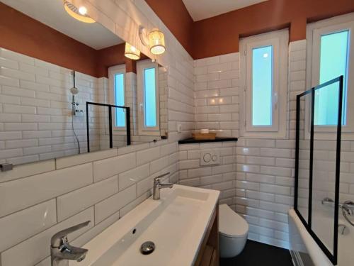 La salle de bains est pourvue d'une baignoire, d'un lavabo et de fenêtres. dans l'établissement Maison de charme dans Sarlat Attention réservations et arrivées commencent exclusivement le dimanche, à Sarlat-la-Canéda