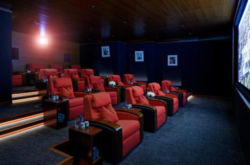 a cinema room with red chairs and a tv at The Peninsula London in London