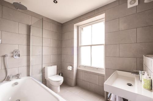 a bathroom with a tub and a toilet and a sink at The Stroud Hotel in Stroud
