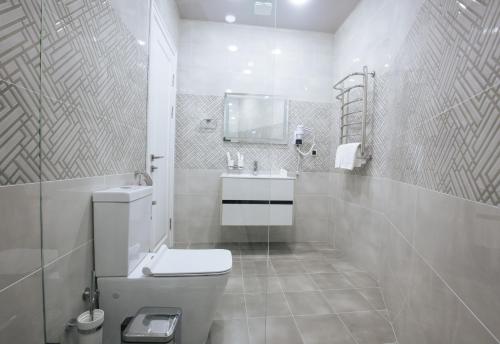 a white bathroom with a toilet and a sink at Ametist Hotel Complex in Samarkand