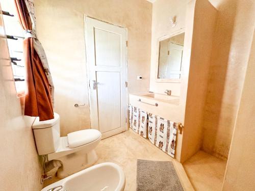 a small bathroom with a toilet and a sink at Dream House in Watamu