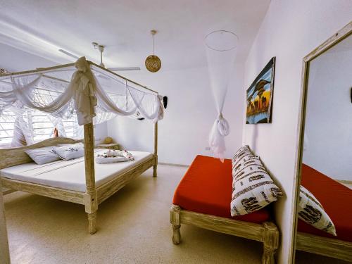 a bedroom with a canopy bed and a red chair at Dream House in Watamu