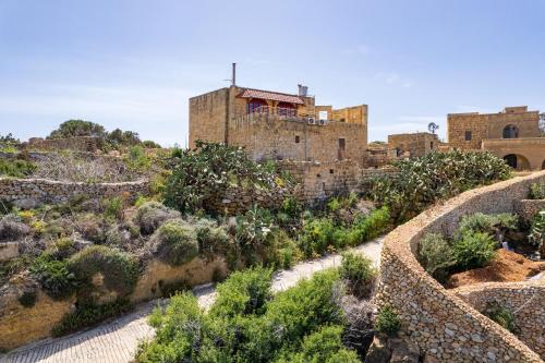 an old building on a hill with bushes at Serene Country House for Beach and Trekking Lovers in Xagħra
