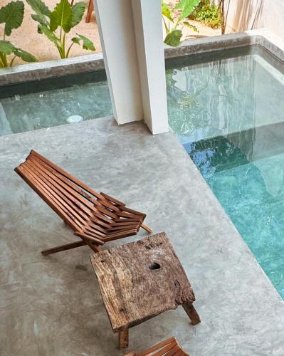a wooden chair sitting next to a swimming pool at COCCOLOBA in Holbox Island