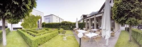 a garden with white tables and chairs on the side of a building at Hotel Schatzmann in Triesen