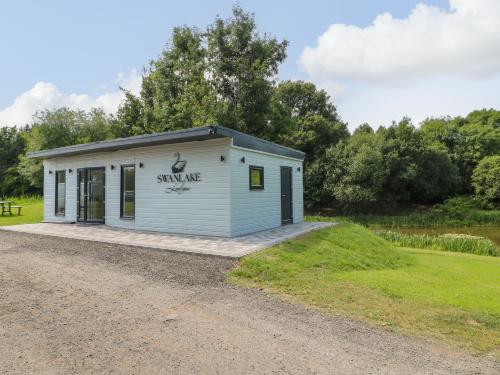 a small white building on a gravel road at Swan Lodge in Coalville