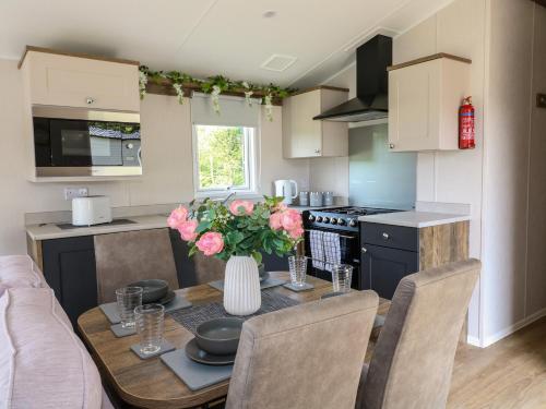 a kitchen with a table with a vase of flowers on it at Swan Lodge in Coalville
