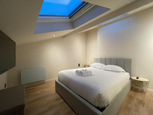 - une chambre avec un grand lit blanc et une lucarne dans l'établissement Cocon sous le toit, 6 personnes, Villeurbanne, à Villeurbanne