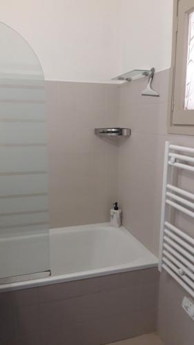 La salle de bains blanche est pourvue d'une baignoire et d'une fenêtre. dans l'établissement Le Gecko Sea View, à Sainte-Maxime