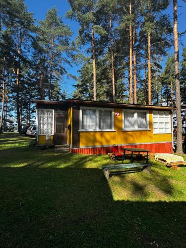 a small yellow and red house in the grass at Vasaras mājiņa pie Rāznas ezera Nr 23 in Ragi