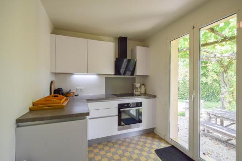 a kitchen with white cabinets and a window at Domaine d'Essendiéras in Saint-Médard-dʼExcideuil