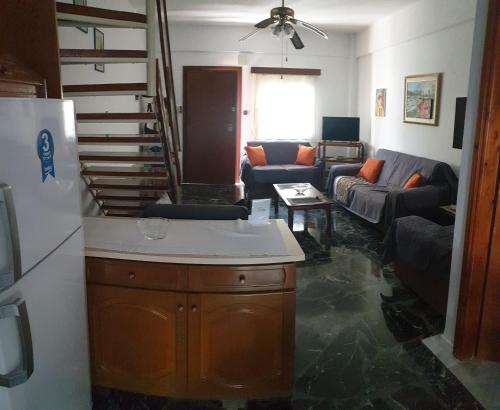a kitchen and a living room with a couch and a refrigerator at Lovely maison house 50m from the beach at Nea Flogita in Flogita