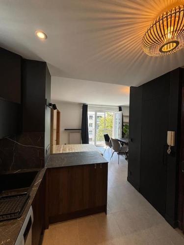 une cuisine avec des placards noirs et un lustre dans l'établissement Studio à Courbevoie 92, à Courbevoie