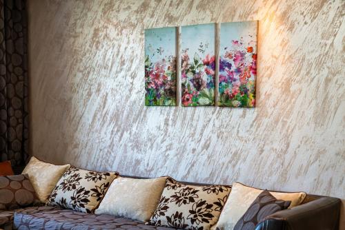 three paintings on a wall above a couch at Apartments Rosina in Plovdiv