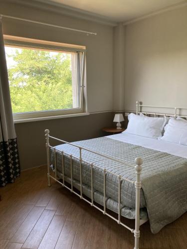 a bedroom with a white bed with a window at La Corte Nascosta Volpedo in Volpedo
