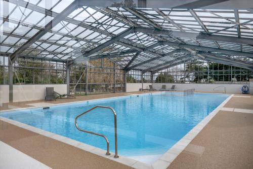 une grande piscine avec un plafond de verre dans l'établissement Piscine - Séjour à Guérande - 3 chambres, à Guérande