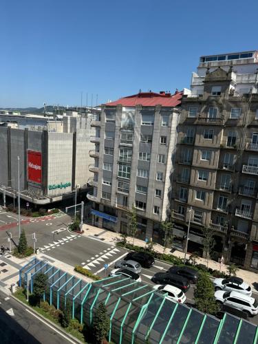 a parking lot with cars parked in front of a large building at Lupita, apartamento en el centro de Vigo in Vigo