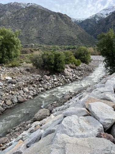 a river with rocks and mountains in the background at Cabaña Nido de Almas in San José de Maipo