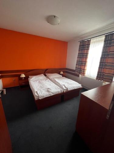 a bedroom with a bed with an orange wall at Penzion Bowling in Liptovský Mikuláš