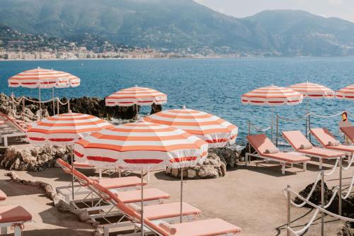 a group of umbrellas and chairs on a beach at The Maybourne Riviera, Maybourne in Roquebrune-Cap-Martin