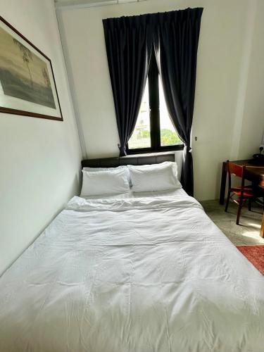 a white bed in a room with a window at Ferringhi Inn 51 in Batu Ferringhi