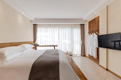 a hotel room with a bed and a flat screen tv at 问安民宿（黄山风景区店） in Huangshan Scenic Area