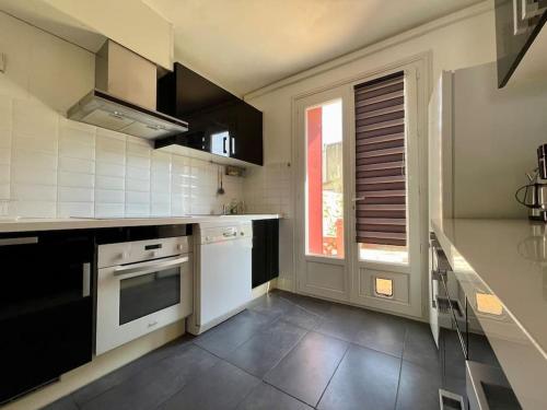 une cuisine avec des appareils en noir et blanc et une fenêtre dans l'établissement Maison Les Bruyères - 3 chambres - jardin et parking à Carcassonne, à Carcassonne