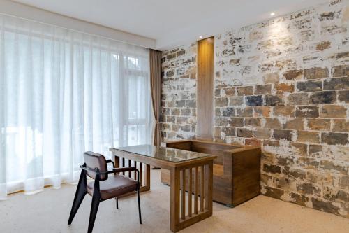 a desk and a chair in a room with a brick wall at 问安民宿（黄山风景区店） in Huangshan Scenic Area