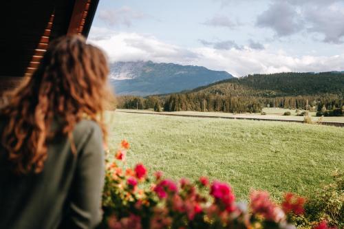 a woman looking out a window at a field of flowers at Appartements K62 in Bad Mitterndorf