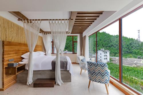 una camera da letto con un letto e una grande finestra di 问安民宿（黄山风景区店） a Mount Huangshan