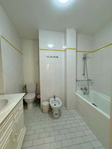 La salle de bains blanche est pourvue de toilettes, d'une baignoire et d'un lavabo. dans l'établissement Marais, Sainte-croix Bretonnerie - 6 places, à Paris