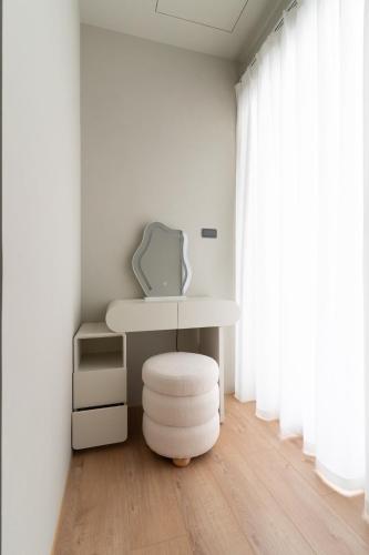 a white table and a stool in a room with a window at Plant House in Chiayi City
