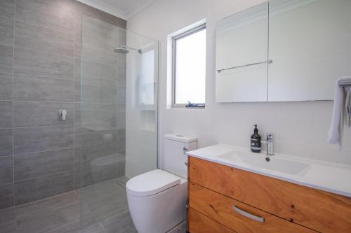 a bathroom with a toilet and a sink and a shower at Spacious 2 Family Accommodation in the Grove in Albany