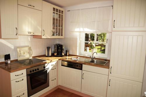 a kitchen with white cabinets and a sink at Ferienhaus Biberburg in Sternberg