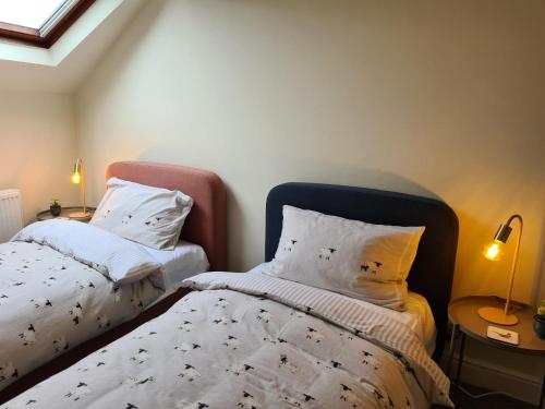 a bedroom with two beds with white blankets and pillows at Heart of Windermere in Windermere