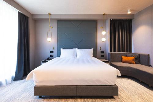 a bedroom with a large white bed and a couch at Crowne Plaza Constanta - Mamaia Beach by IHG in Mamaia
