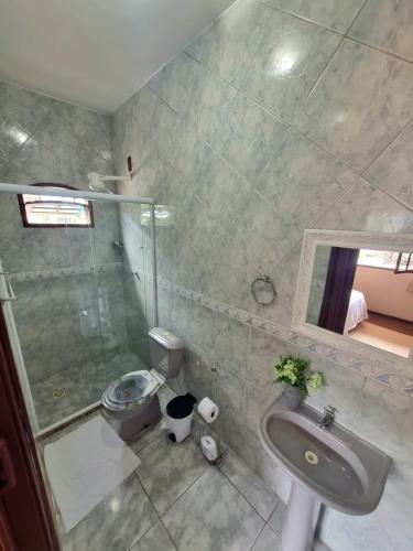 a bathroom with a sink and a shower and a toilet at Pousada Tuiuiu in Angra dos Reis