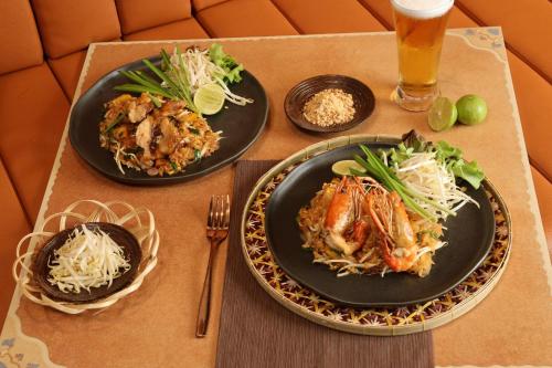 a table with three plates of food and a glass of beer at WE HOTEL RIVERFRONT in Bang Su